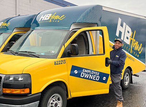 Employee standing outside of truck holding door open that reads "Employee Owned"