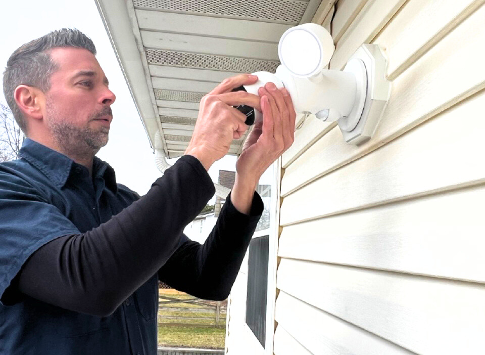 electrician installing an outdoor floodlight with camera