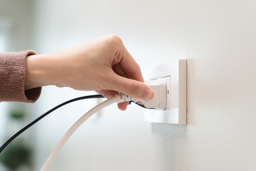 hand plugging in a charger into a wall outlet to show the importance of whole-home surge protection